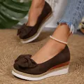 Primer plano de mocasines con plataforma marrón para mujer con lazo y cuña gruesa. - Marrón Oscuro