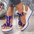 Detailansicht weißer Keilsandaletten mit blauen Schmetterlingen und glitzerndem Strass-Plateau. - Blau