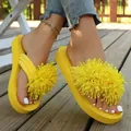 Primer plano de chanclas de plataforma amarillas con detalles de pompones florales y suelas gruesas - Amarillo