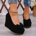 Primo piano di eleganti décolleté con zeppa in camoscio nero con fiocco e plateau - 36 / Nero