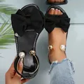 Stylish black flat sandals with oversized bow and pearl-embellished ankle strap - Black