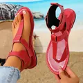 Detalle de sandalias planas rojas de cuero con hebilla sobre fondo de playa - 36 / Rojo
