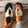 Dettaglio di sandali infradito bianchi con una grande fibbia decorativa in metallo dorato - Nero e Bianco