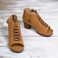 Close-up shot of stylish tan chunky heel sandals with cutout design on white wooden floor - 36 / Camel