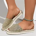 Close-up of sparkly gold sequin peep-toe flat sandals worn with a beaded anklet. - 38 / Gold