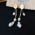 Vue détaillée des disques dorés froissés et des élégantes perles irrégulières de la boucle - Or