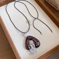 Close-up detail van Boheemse hartketting met witte stippen en verfijnde kwastjes van kralen - Zwart Koffie Wit