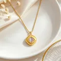 Detailed macro view of a minimalist gold square zircon pendant necklace on a white plate - Necklace / Gold