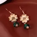 Nahaufnahme von Vintage-Goldblumenohrringen mit eleganten grünen Glaslaternenperlen - Ohrhaken / Gold Grün