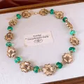 Halskette im Vintage-Stil mit goldenen Blumenanhängern und grünen Glasperlen Detail - Halskette / Gold Grün