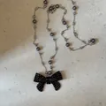 Detailweergave van een parelketting met een zwart gestipte strik hanger van acryl. - Zwart