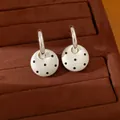 Detailansicht von weißen runden Ohrringen mit schwarzen Punkten an silbernen C-Haken - Rund / Weiß