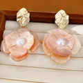 Close-up of elegant acrylic flower earrings with faux pearls and gold-plated details - Gold-Pink