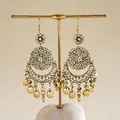 Boucles d'oreilles pendantes dorées avec découpes géométriques sur un support à bijoux. - 7# Style Crochet d'Oreille / Or