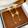 Macro-weergave van elegante gouden vlinder-oorbellen met kristallen in een doosje - Goud