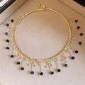 Close-up of gold beaded choker necklace with intricate black bead fringe detail. - Choker Necklace / Gold-Black