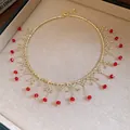 Detail view of a gold choker necklace with elegant red beaded fringe tassels and gold link. - Choker Necklace / Gold-Red