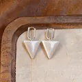 Close-up of minimalist silver hoop earrings featuring white pearlescent triangle pendants. - Pearly White Triangle Pendant / Matte Silver