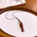 Gedetailleerd overzicht van een houten vis hanger ketting op een minimalistisch houten dienblad. - Ovaal / Bruin