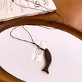 Detailweergave van een houten vis hanger aan een zwarte koordketting in een rustiek dienblad. - Gebogen Vorm / Donker Koffie