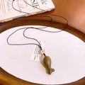 Gedetailleerde weergave van houten vis hanger ketting met bruin gevlochten koord - Lichtkoffie