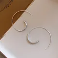 Nahaufnahme von minimalistischen silbernen Creolen mit poliertem Finish auf Leder - Ohrhaken-Stil / Silber