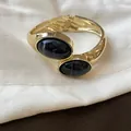 Dettaglio del bracciale rigido dorato con pietre in resina nera marmorizzata - Oro-Nero