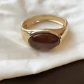 Dettaglio di un bracciale dorato vintage con un inserto ovale in resina ambra - Piccolo / Marrone oro