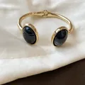 Dettaglio ravvicinato di un bracciale rigido dorato con resina nera effetto marmo - Piccolo / Oro-Nero