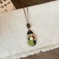Detailed view of a retro wooden pendant necklace with vintage buttons and a green tassel - Retro Button Tassel Necklace