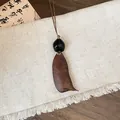 Close-up of a rustic wooden geometric pendant on a textured linen background. - Geometric Wood Bead Seed Pod Necklace