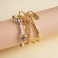 Dettaglio del set di 4 bracciali dorati con ciondoli malocchio e perle su carta - Set da 4 pezzi / Set di 4 / Oro