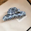Detail view of a blue and green plaid bow hair claw clip on a beige textured background. - Plaid Bow Claw Clip / Green
