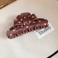 Detailed macro shot of a brown retro bow hair claw clip with white star patterns - Star Bow Claw Clip / Brown