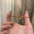 Détail d'un bracelet tressé rouge avec breloque hulu dorée et zircon étincelant - Round Zirconia Red Rope Bracelet / Or Rouge