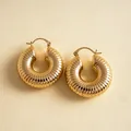 Detailaufnahme von goldenen klobigen Creolen mit einer eleganten gerippten Oberflächenstruktur - Ohrringe / Gold
