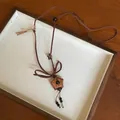 Detailed view of a cute wooden star pendant necklace with brown cord and decorative beads - Star / Brown