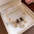 Detaillierte Ansicht des goldenen Armreifs mit Stern- und Mondanhängern in einer Geschenkbox - Gold-Schwarz