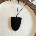 Gedetailleerde weergave van een zwarte lederen ovale hangerketting op een keramisch bord. - Zwart
