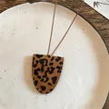 Detailopname van een leren halskettinghanger met luipaardprint en witte stiksels - Donkere Koffie Luipaard