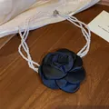 Detail eines Vintage-Perlen-Chokers mit einer großen schwarzen Satin-Rose verziert. - Weiß-Schwarz