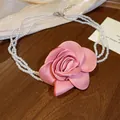 Nahaufnahme einer Vintage-Perlenkette mit einer großen rosa Stoffrose. - Weiß-Rosa