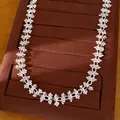 Close-up van elegante geometrische zirkonia ketting op een bruine fluwelen sieradendisplay - Zilver