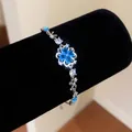 Macro view of a sparkling silver bracelet with a blue zircon flower on a black display - Flower Style / Silver-Blue