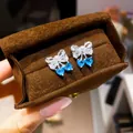 Exquisite silver bow stud earrings featuring white zircon and blue heart-shaped drops - Silver-Blue