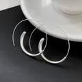 Detailaufnahme von übergroßen minimalistischen silbernen Creolen auf schwarzem Grund. - Spiralförmiger Kreistyp / Silber