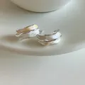 Gros plan sur d'élégantes boucles d'oreilles plissées avec finition blanc et or - Argent et Or Bicolore