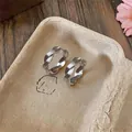 Nahaufnahme von verdrehten silbernen Metall-Ohrklemmen im minimalistischen Design - Ohrringe / Silber