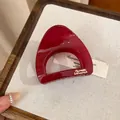 Gros plan d'une pince à cheveux en acrylique rouge brillant avec détail du logo. - Rose rouge
