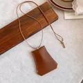 Detailed macro view of a brown leather bag-shaped pendant necklace with white stitching. - Bag Shaped Style (HN13696) / Brown